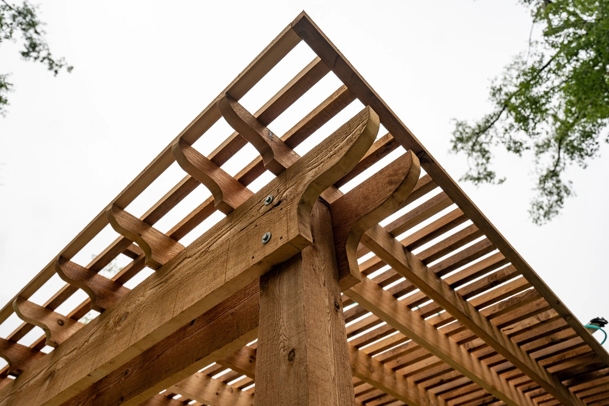 Détail d'une pergola en bois avec des lames et des fixations métalliques, montrant la qualité de la construction et des matériaux utilisés par MABO.